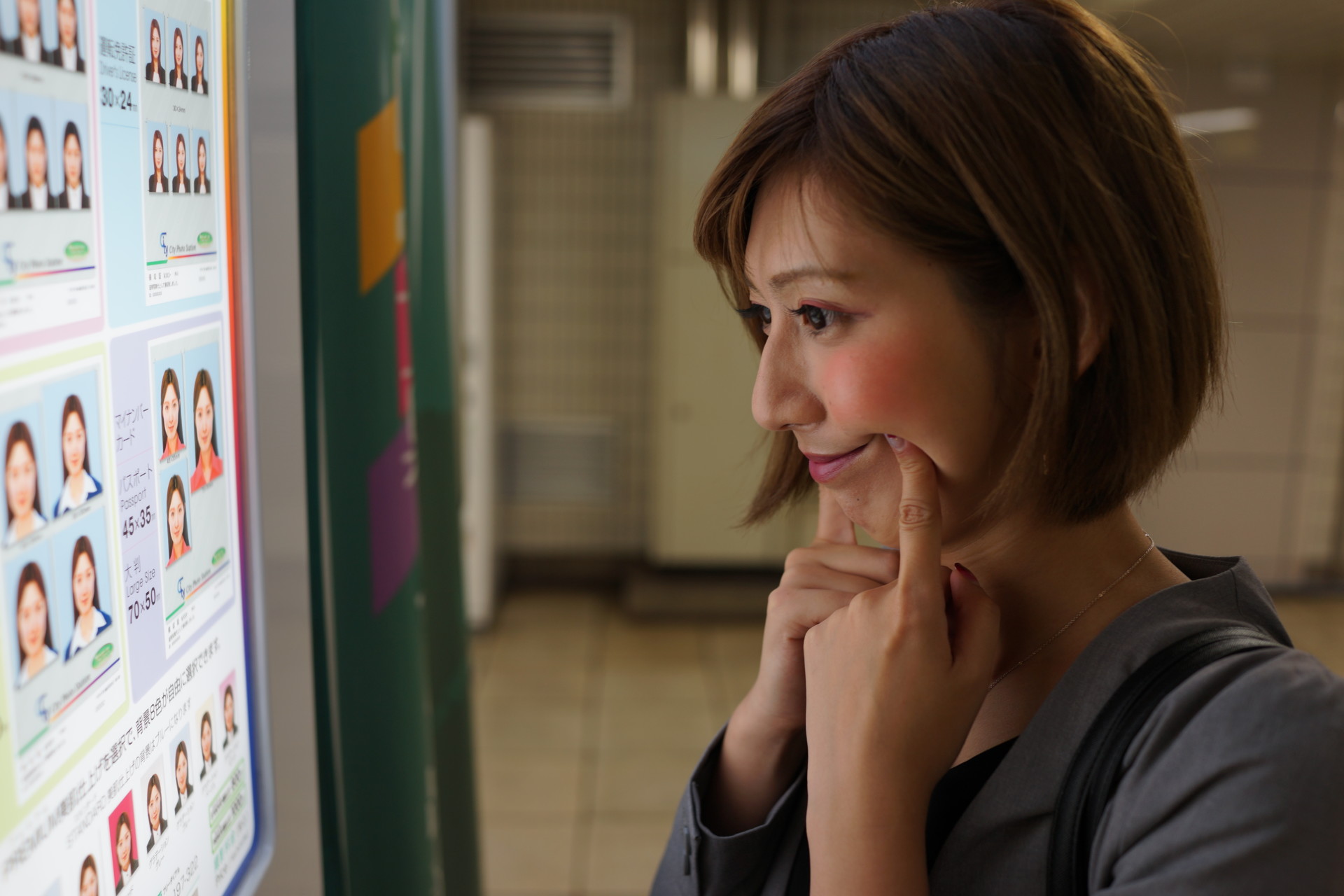 スピード写真の前で表情の練習をする女性