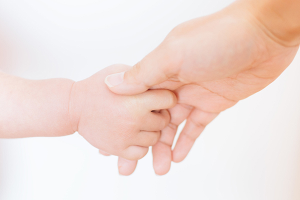赤ちゃんと手をつなぐ大人の手