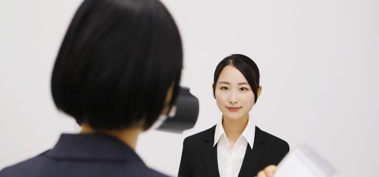 まっすぐ前を向いて証明写真を撮る女性